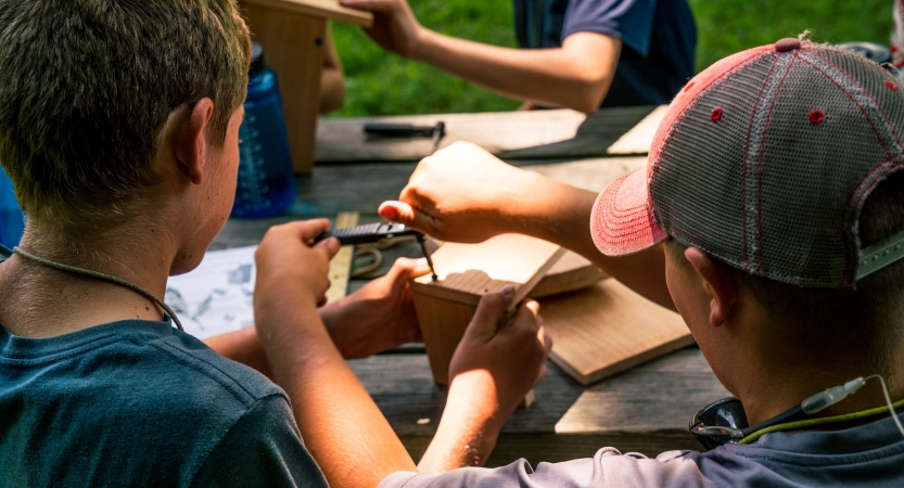 Two people use tools and wood during a service project. 